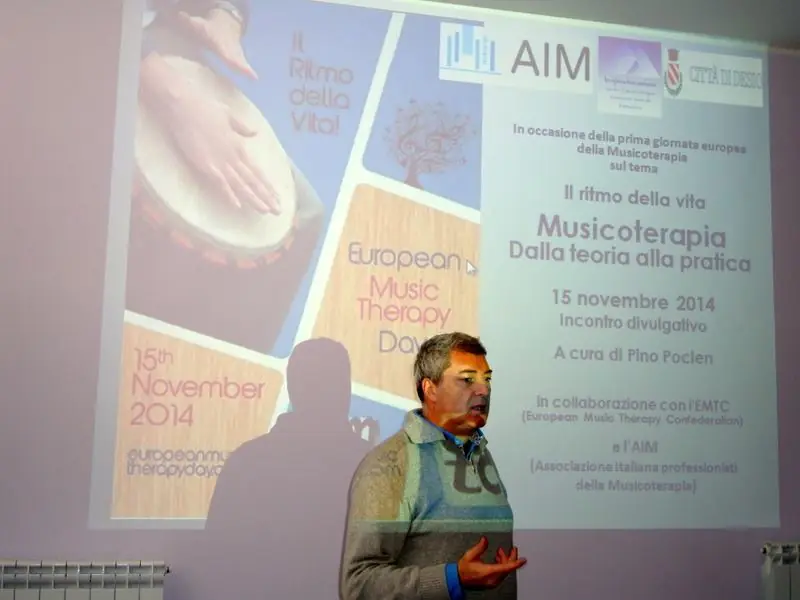 Pino Poclen presenta un incontro sulla musicoterapia davanti a una proiezione