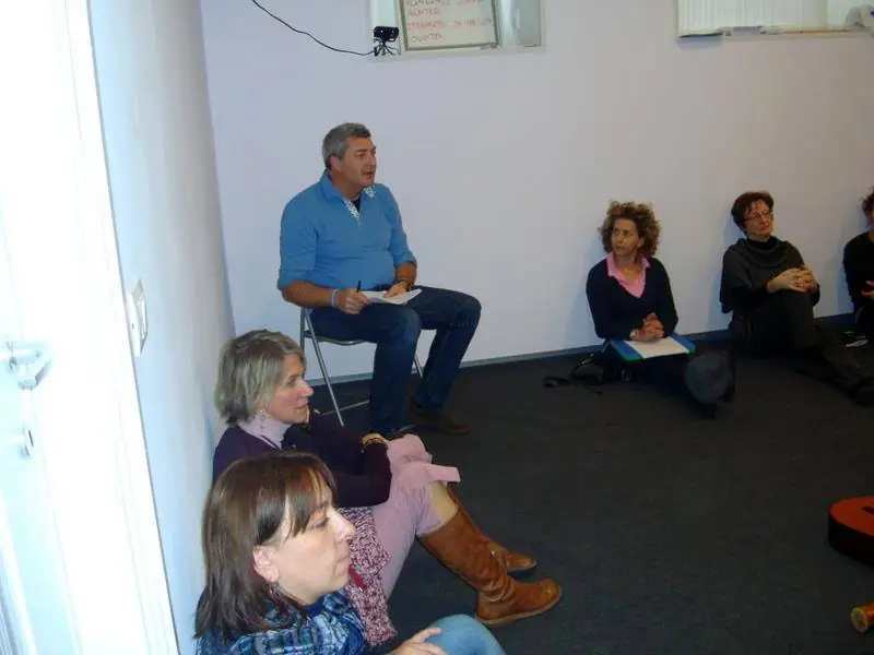 Pino Poclen seduto in cerchio con un gruppo di persone durante un incontro di musicoterapia